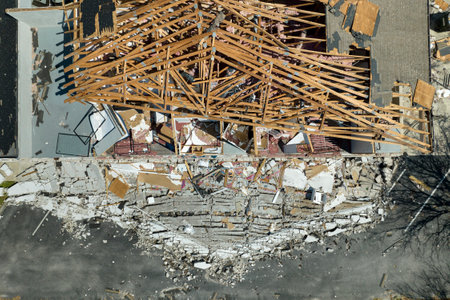 Ruined building in need of repair. Wind damaged house roof with missing asphalt shingles and...