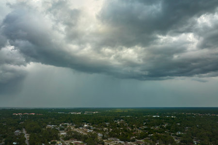 Dark stormy clouds forming on gloomy sky before heavy rainfall over suburban town area