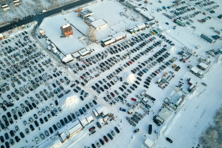 Aerial view of vehicle open market lot with many cars for sale parked and people customers walking...