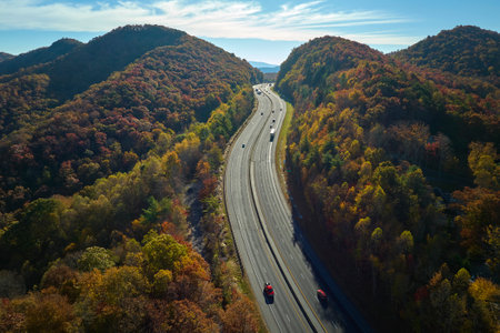 I-40 freeway road leading to Asheville in North Carolina thru Appalachian mountains with yellow fall forest and fast moving trucks and cars. Concept of high speed interstate transportationの写真素材