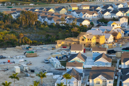 Unfinished frames of inexpensive homes with wooden roof beams under construction. Development of...