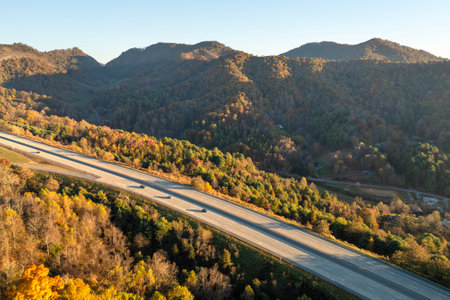 Wide multilane highway road in USA Appalachian mountains with fast driving cars. Above view of...
