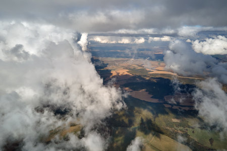 Aerial view from airplane window at high altitude of earth covered with white puffy cumulus clouds