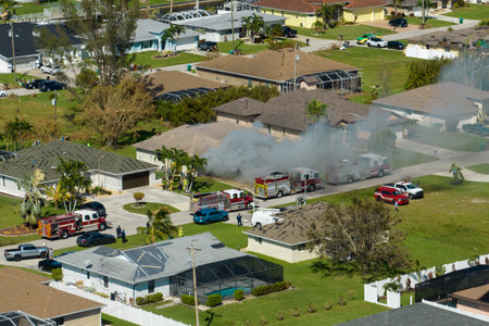 Aerial view of house on fire and firefighters extinguishing flames after short circuit caused spark...