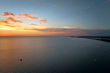Aerial view of lonesome white yacht at sunset floating on sea waves with ripple surface. Motor boat recreation on ocean surfaceの写真素材
