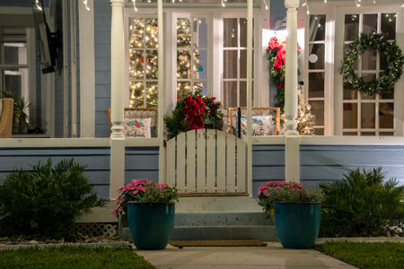 Brightly illuminated Christmas decorations on front yard porch of Florida family home. Outside decor for winter holidaysの写真素材