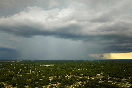 Dark stormy clouds forming on gloomy sky during heavy rainfall season over suburban town area
