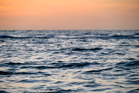 Dramatic red ocean waves at sunset with soft evening sea dark water