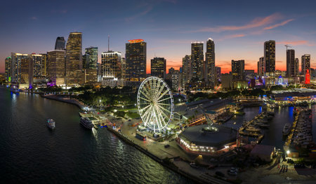 High illuminated skyscrapers of Brickell, citys financial center. Skyviews Miami Observation Wheel at Bayside Marketplace with reflections in Biscayne Bay water and US urban landscape at nightの写真素材