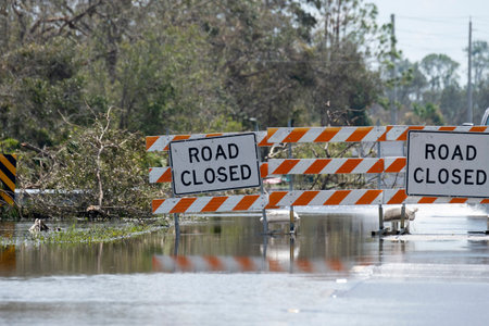 Hurricane flooded street with road closed signs blocking driving of cars. Safety of transportation...