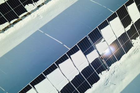 Aerial view of electrical power plant with solar panels covered with snow melting down in winter end for producing clean energy. Concept of low effectivity of renewable electricity in northern regionの写真素材