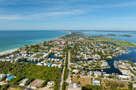 Expensive mansions between green palm trees on Gulf of Mexico shore in island small town Boca Grande on Gasparilla Island in southwest Florida, USA. Aerial view of wealthy waterfront neighborhoodの写真素材