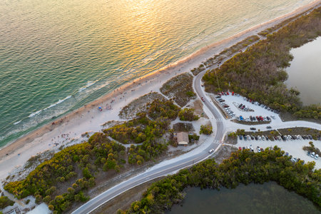 Parking lot for tourists cars in front of ocean beach with soft white sand in Florida. Popular vacation spot at sunsetの写真素材