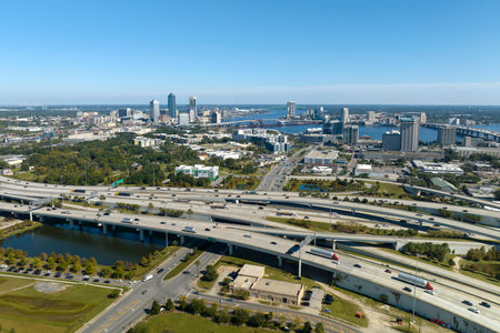 Aerial view of Jacksonville city with high office buildings and american freeway intersection with fast driving cars and trucks. View from above of USA transportation infrastructureの写真素材