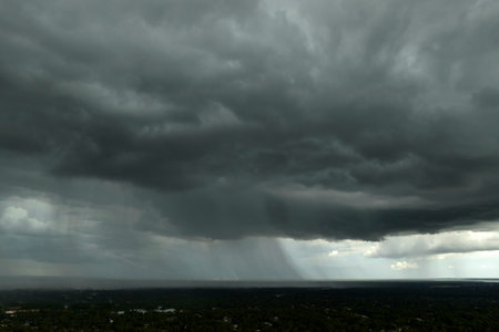 Heavy rain falling down from stormy clouds during thunderstorm on dark sky. Moving and changing cloudscape weatherの写真素材