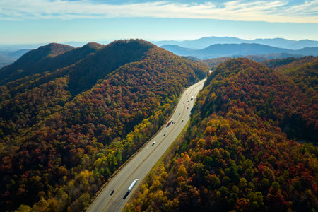 I-40 freeway road leading to Asheville in North Carolina thru Appalachian mountains with yellow fall forest and fast moving trucks and cars. Concept of high speed interstate transportationの写真素材