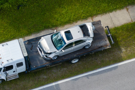 Traffic accident with tow truck hauling smashed vehicle on car crash site. First responders helping on road emergency in Florida, USAの写真素材
