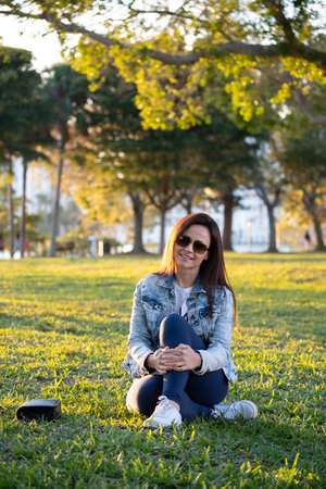 Woman sitting on grass in city park on summer dayの写真素材