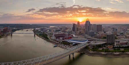 Highway traffic with driving cars on bridge in downtown district of Cincinnati city in Ohio, USA. American city skyline with brightly illuminated high commercial buildings at sunsetの写真素材