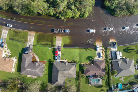 Flooded american street with moving vehicles and surrounded with water houses in Florida residential...