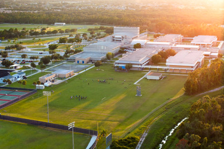 Sports education in USA schools. School children playing American football game during physical exercise on school stadium at sunsetの写真素材