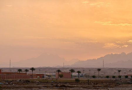 Sunset landscape with remote building complex against dark mountain peaks in desertの写真素材