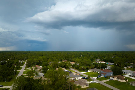 Dark stormy clouds forming on gloomy sky during heavy rainfall season over suburban town areaの写真素材