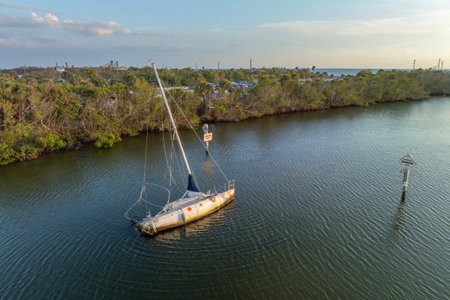 Half sunken sailing yacht capsized on shallow bay waters after hurricane Ian in Manasota, Florida