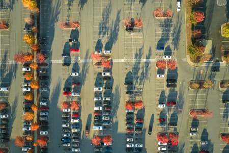 Top view of many cars parked on a parking lot in front of a strip mall plaza. Concept of consumerism and market economyの写真素材