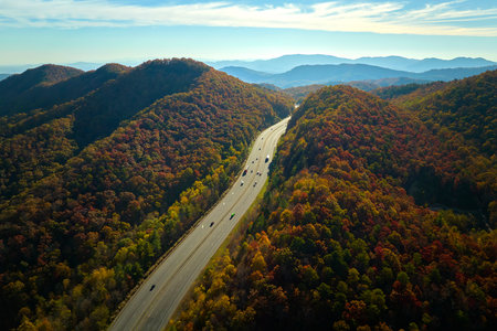View from above of I-40 freeway route in North Carolina leading to Asheville thru Appalachian mountains with yellow fall woods and fast moving trucks and cars. Interstate transportation conceptの写真素材