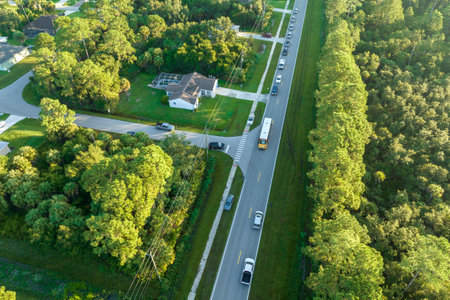 Aerial view of yellow school bus picking up children at sidewalk bus stop for their lessons in early morning. Public transportation in the USAの写真素材