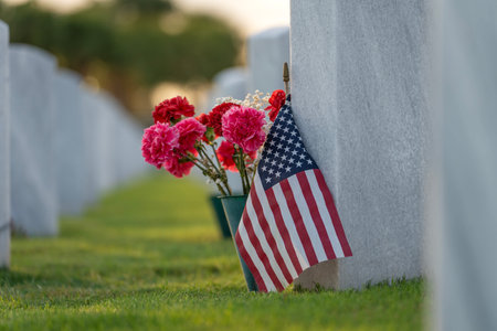 American national military cemetery with rows of white tomb stones with flowers and USA flags on green grass lawn. Memorial Day conceptの写真素材