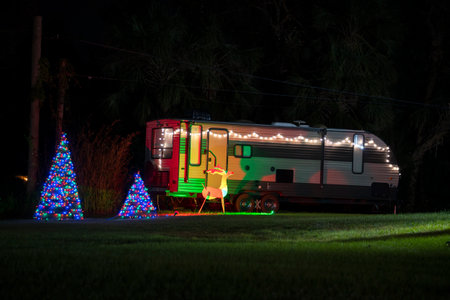 Brightly illuminated christmas decorations on front yard near camper van. Outside decor for winter holidaysの写真素材