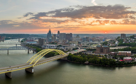 Downtown district of Cincinnati city in Ohio, USA at sunset with driving cars traffic on Daniel Carter Beard Bridge and brightly illuminated high skyscraper buildings. American travel destinationの写真素材