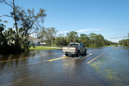 Hurricane flooded street with moving cars in surrounded with water Florida residential area. Consequences of natural disasterの写真素材