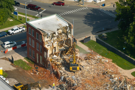 Old building demolition site. Construction excavator tearing down obsolete brick walls of Historic Edwards Building in Berea, Kentucky, USA. City planning conceptの写真素材