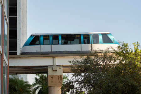 Urban transportation in downtown district of Miami Brickell in Florida USA. Metrorail city train car on high railroad over street traffic between skyscraper buildings in modern American megapolisの写真素材