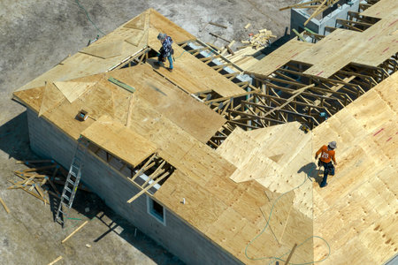 Aerial view of builders working on unfinished residential house with wooden roof frame structure under construction in Florida suburban areaの写真素材