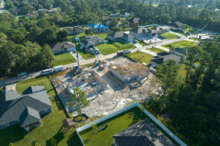 Aerial view of builders working on unfinished residential house with wooden roof frame structure under construction in Florida suburban areaの写真素材
