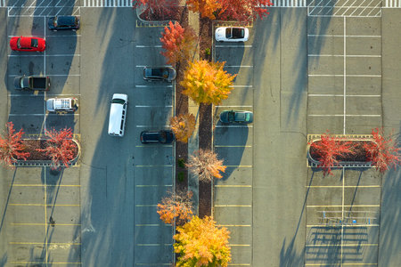 Aerial view of large parking lot with many parked colorful cars. Carpark at supercenter shopping mall with lines and markings for vehicle places and directionsの写真素材