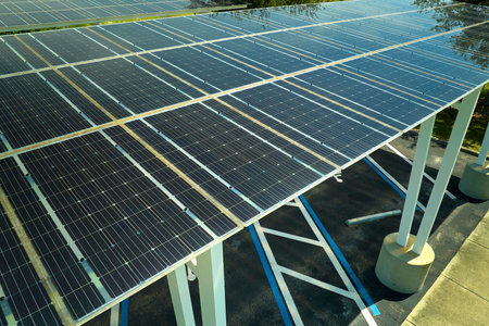 Aerial view of solar panels installed as shade roof over parking lot for parked cars for effective generation of clean electricity. Photovoltaic technology integrated in urban infrastructureの写真素材