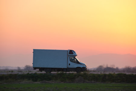 Cargo truck driving on highway hauling goods in evening. Delivery transportation and logistics conceptの写真素材