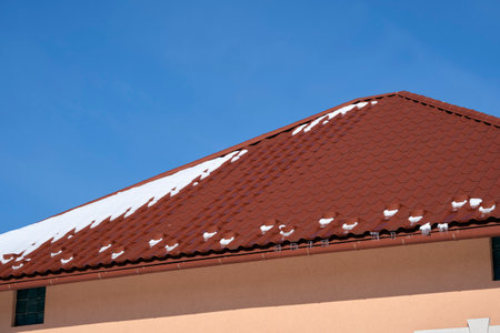 Closeup of house roof top covered with snow in cold winter. Tiled covering of building in wintertime weatherの写真素材