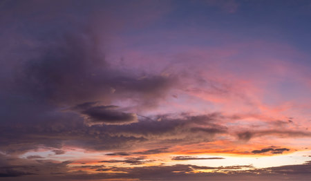 Colorful sunset sky with setting sun behind vivid orange and yellow cloudsの写真素材