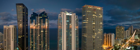 Night urban landscape of downtown district in Sunny Isles Beach city in Florida, USA. Skyline with brightly illuminated high skyscraper buildings in modern american megapolisの写真素材