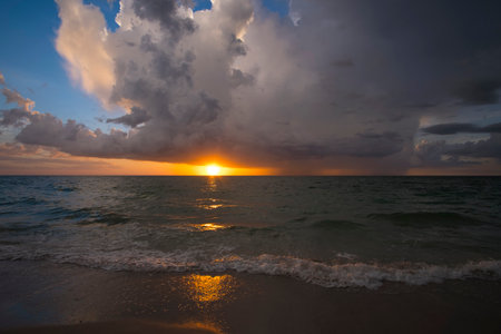 Ocean landscape with clouds over rough evening sea water waves crushing on sandy beach. Beautiful seascape at sunsetの写真素材