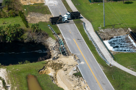 Roadblock at damaged road bridge destroyed by river after flood water washed away asphalt. Rebuilding of ruined transportation infrastructureの写真素材