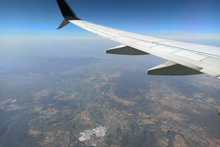 View through airplane window of commercial jet plane wing flying high in the sky. Air travelling conceptの写真素材