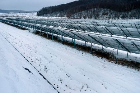 Aerial view of sustainable electrical power plant with solar photovoltaic panels covered with snow...