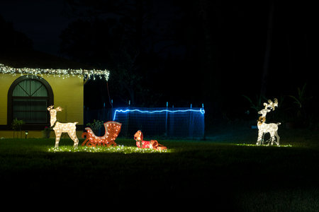 Brightly illuminated christmas decorations on front yard of florida family home. Outside decor for winter holidaysの写真素材